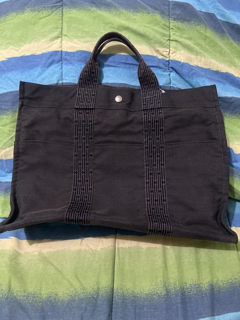 Hermes Herline Tote Bag (Category: Luxury Bags & Wallets) located in Pasay City. Submitted by damoreluxe (Listing ID 1436540184, Image 1). Description: - please self authenticate Hermes Herline black/gray tote bag - Black canvas exterior with leather accents - Spacious main compartment with zipper closure - Interior pocket included - Top handle for carrying - Secure snap closure - Hermes logo visible on interior label and snap button.
