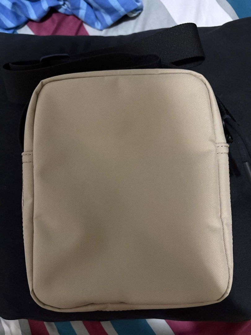 Lacoste Men's Classic Crossbody Bag (Category: Sling Bags) located in Quezon City. Submitted by lhiz.lhiz (Listing ID 1436551283, Image 2). Description: - Lacoste crossbody bag - Beige exterior, black strap - Zippered main compartment - Interior pocket - Lacoste logo on front and inside - Includes tag.