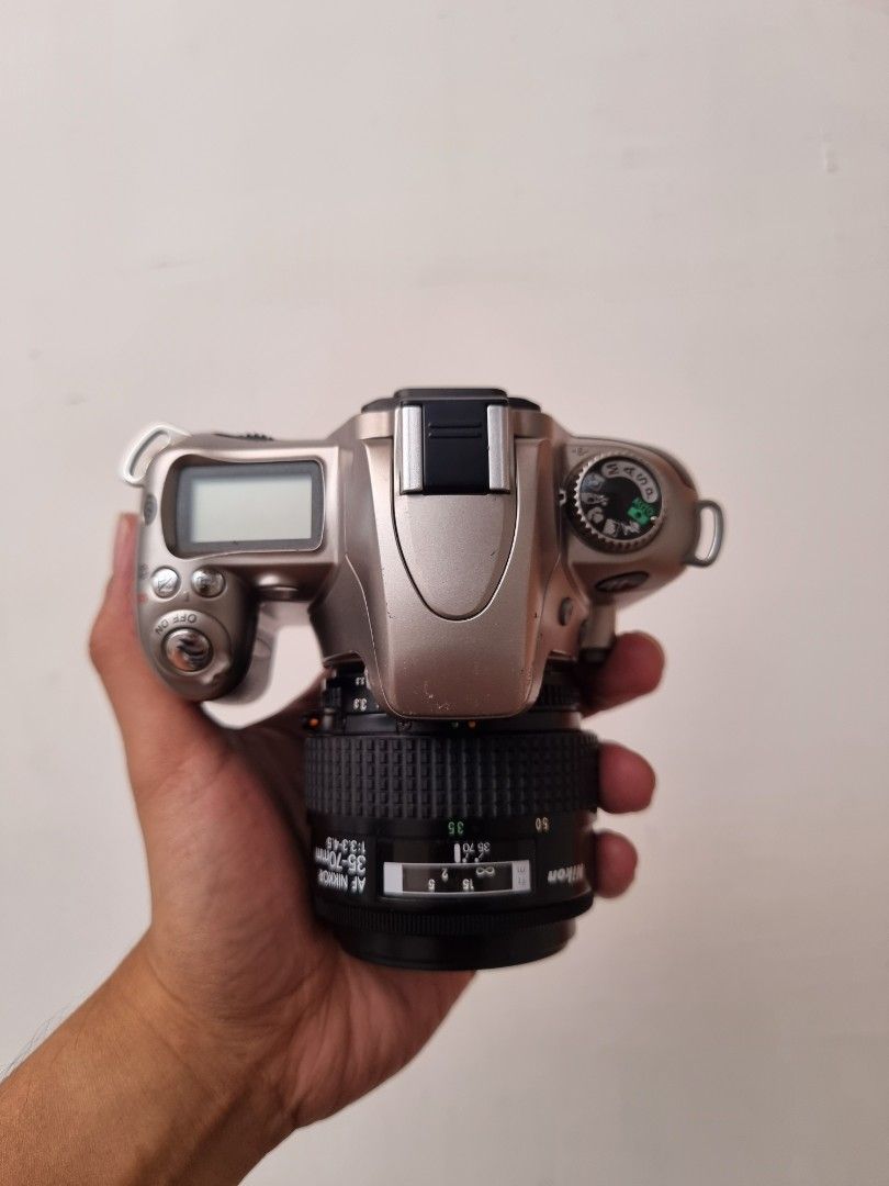 Nikon SLR Camera with Lens (Category: Cameras) located in San Fernando. Submitted by filmburrrn_ (Listing ID 1436528272, Image 1). Description: no issue. this is a film camera. not dogital. - Nikon SLR camera - Includes 35-70mm lens - Silver camera body - Black lens finish - Built-in display screen - Top-mounted mode dial - Nikon logo on front.