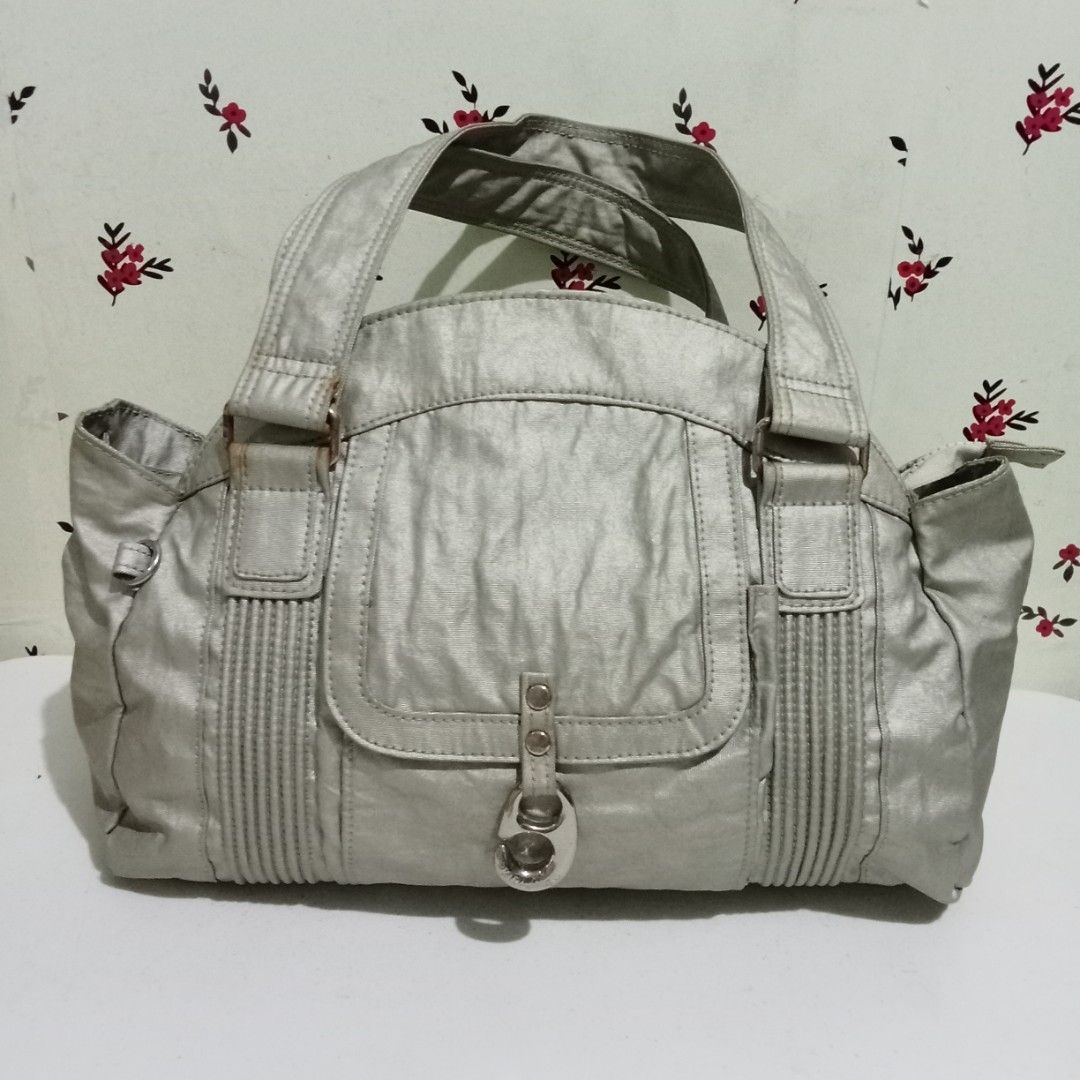 KIPLING Silver Handbag with Pocket Detail (Category: Luxury Bags & Wallets) located in Hinigaran. Submitted by faye_fab02 (Listing ID 1436508921, Image 1). Description: - Silver handbag - Front pocket - Clasp closure - Double handles and shoulder strap - Textured appearance - Vertical pleat details - Spacious main compartment - Side pockets - Silver-toned hardware.