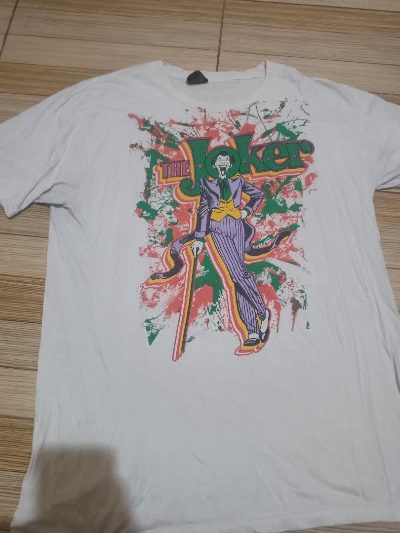 The Joker DC Comics T-shirt (Category: Tshirts & Polo Shirts ) located in Manila. Submitted by chengg_08 (Listing ID 1436606512, Image 1). Description: - DC Comics Joker t-shirt - Classic Joker graphic with cane - Dated 2005 - Crew neck - Short sleeves - Colorful print with green, red, and purple accents.