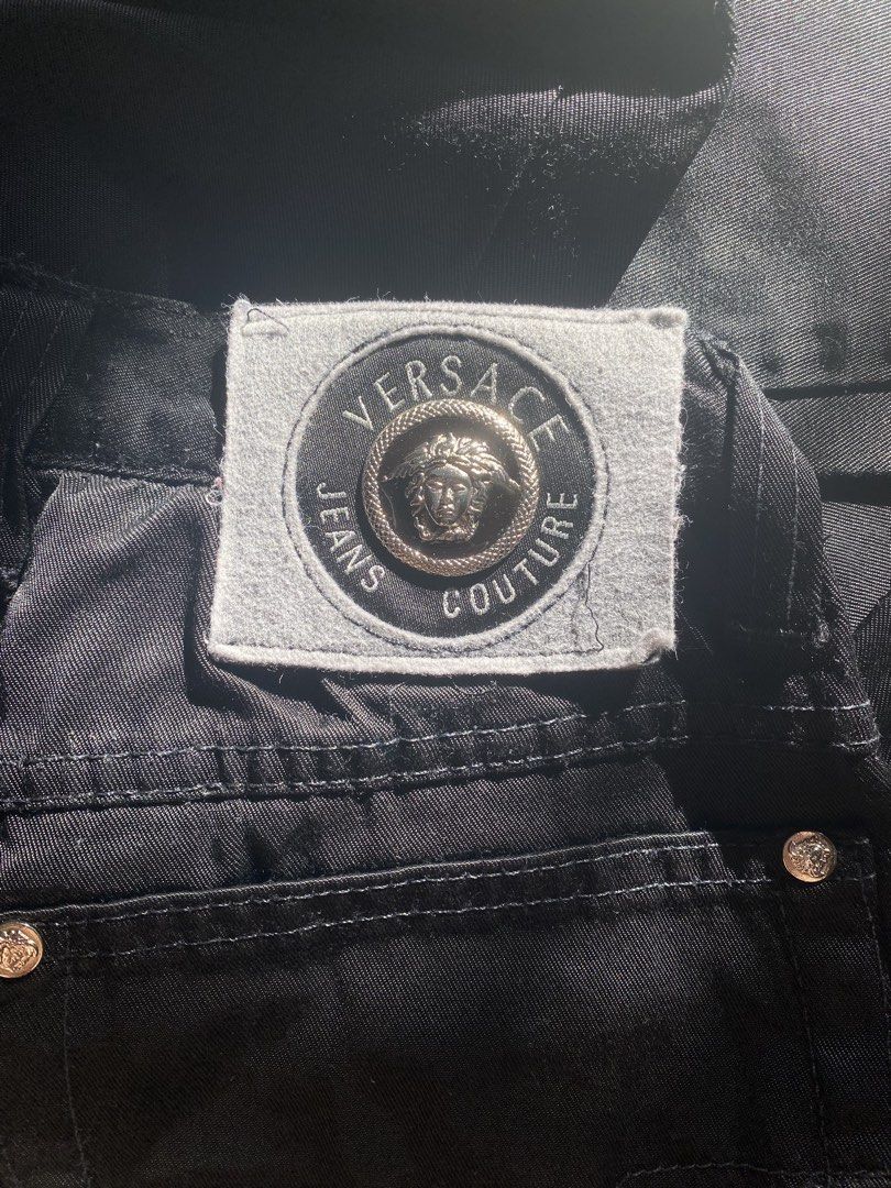 Versace Jeans Couture Black Jeans (Category: Luxury Apparel) located in Gapan. Submitted by sonikku (Listing ID 1436513312, Image 2). Description: Black Versace Jeans Couture jeans. Features a button closure with the Versace logo. Includes the Versace Jeans Couture patch on the back pocket. The jeans have a straight leg fit. The interior tag is visible. The jeans have a classic five-pocket design. Fits waist size 27”-28”.