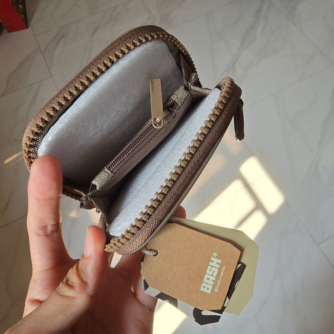 BASH Manila Square Wallet (Category: Wallets & Card holders) located in Taguig. Submitted by thriftzzzy (Listing ID 1436800623, Image 2). Description: - BASH Manila square wallet - Features a zip closure - Includes a small front pocket - Interior has a small compartment - Available colors: Brown and Black - Comes with original tag.