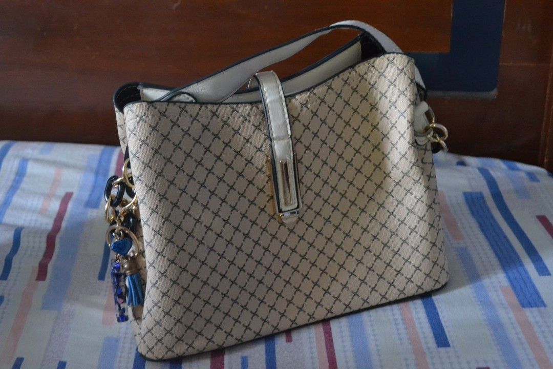 Beige Crossbody Handbag with Pattern (Category: Luxury Bags & Wallets) located in Valenzuela. Submitted by miss_merix (Listing ID 1436731686, Image 2). Description: - Beige handbag with a unique patterned design - White strap - Flap closure with gold-colored button - Multiple compartments, including a zippered one - Decorative charm included - Suitable for everyday use.