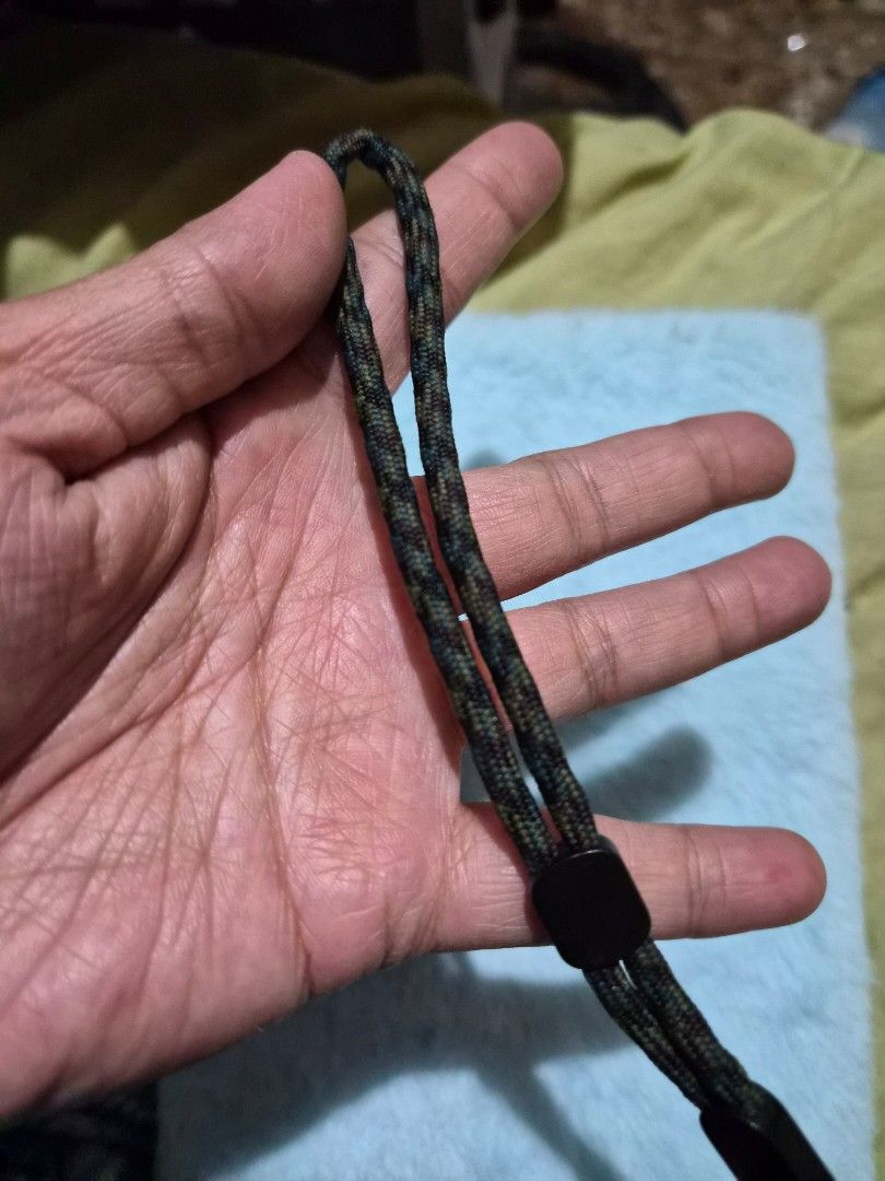 Braided Phone Lanyard (Category: Other Mobile & Gadget Accessories) located in Mandaue City. Submitted by chuchi152615 (Listing ID 1436696187, Image 3). Description: - Braided wrist strap - Black and green camouflage pattern - Features black plastic connectors - Includes a small black string - Durable design - Ideal for cameras and small devices - Provides added security.