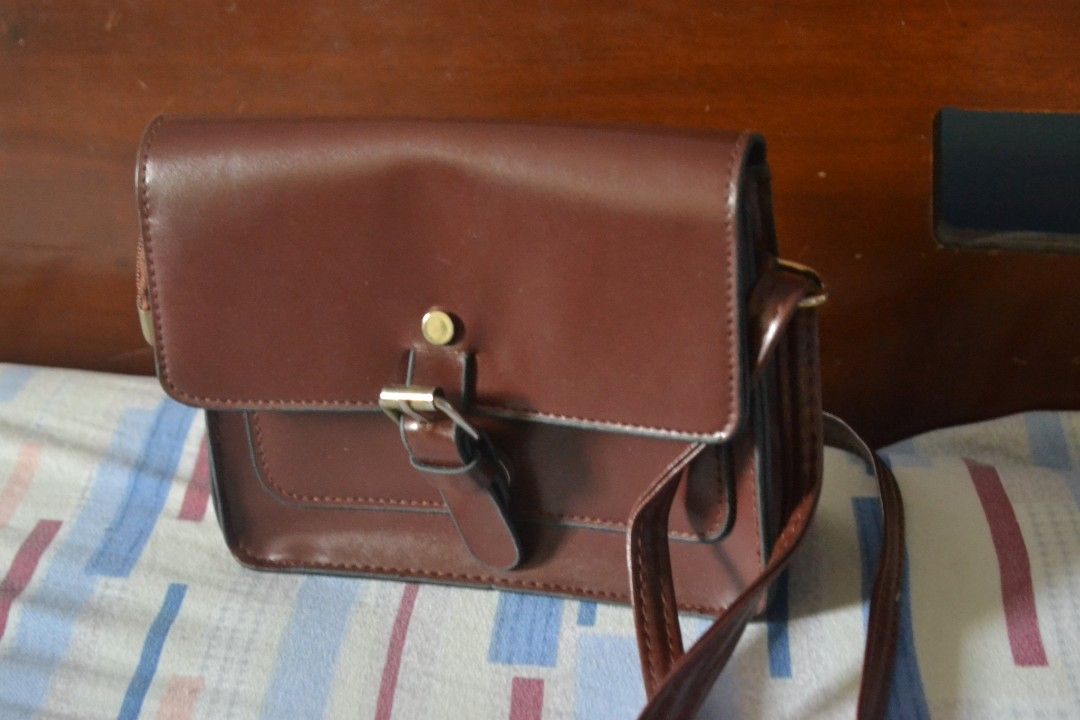 Brown Crossbody Bag (Category: Cross-body Bags) located in Valenzuela. Submitted by miss_merix (Listing ID 1436730799, Image 1). Description: - Brown crossbody bag - Flap closure with buckle - Long strap for shoulder or crossbody wear - Pure leather - From Saudi Arabia - Single main compartment with zipper - Rectangular shape - Darker interior lining.