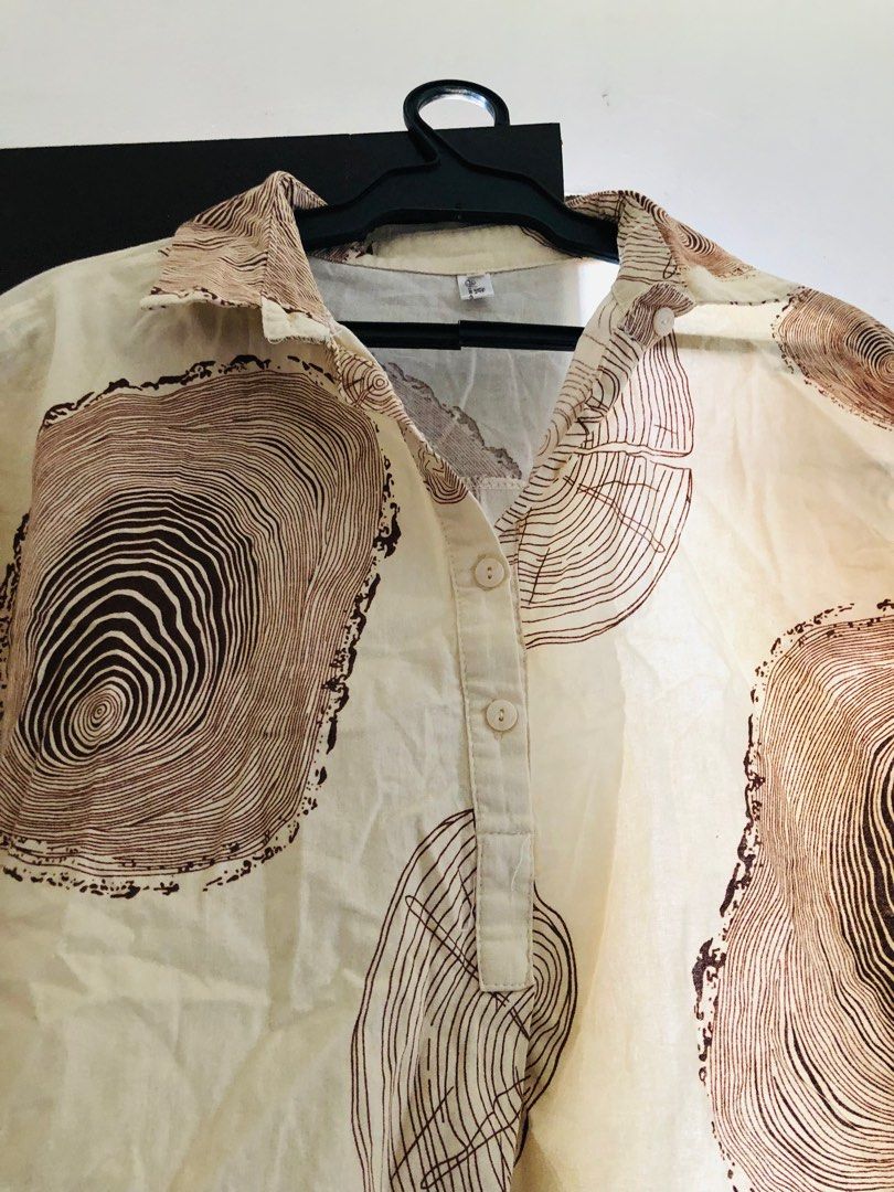 Cream Oversized Wood Grain Print Top (Category: Blouses) located in Las Pinas. Submitted by bibliomomma (Listing ID 1436699674, Image 2). Description: Lightweight cream collared top with an eye-catching wood grain/tree ring print in brown tones. Features a relaxed oversized fit, short sleeves, and partial button-down front for an effortless casual look. Made from breathable fabric that’s comfortable for everyday wear, perfect for pairing with jea