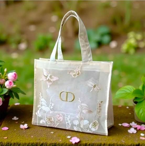 Dior Complimentary Gift Tote Bag (Category: Luxury Bags & Wallets) located in Manila. Submitted by mayserrano16 (Listing ID 1436664127, Image 1). Description: - Dior Gift Tote Bag - Delicate design with embroidered butterflies and floral details - Transparent body - Cream-colored trim and handles - Gold 'CD' logo - Complimentary gift bag.