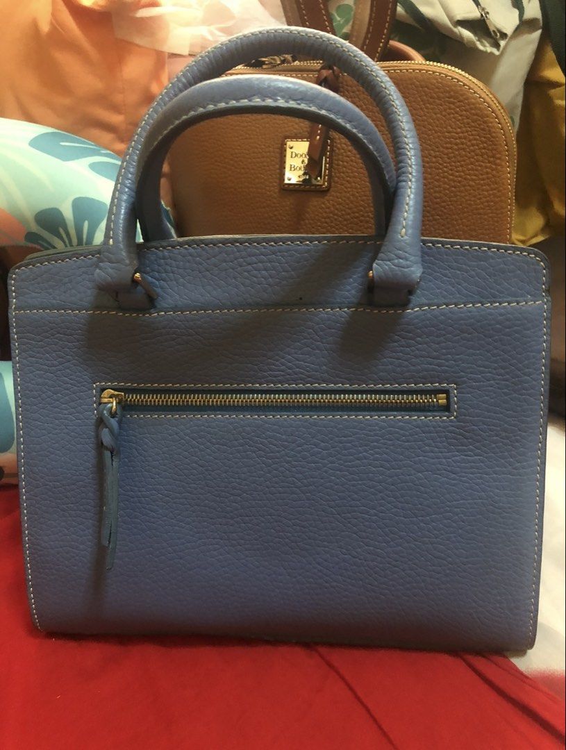 Dooney & Bourke Blue Satchel Handbag (Category: Luxury Bags & Wallets) located in Quezon City. Submitted by cprmob (Listing ID 1436755951, Image 3). Description: - Dooney & Bourke satchel handbag - Light blue pebbled leather exterior - Top handle design - Zipper closure - Back zipper pocket - Includes tag - Gold-tone hardware - Brown interior - Protective metal feet at the bottom.