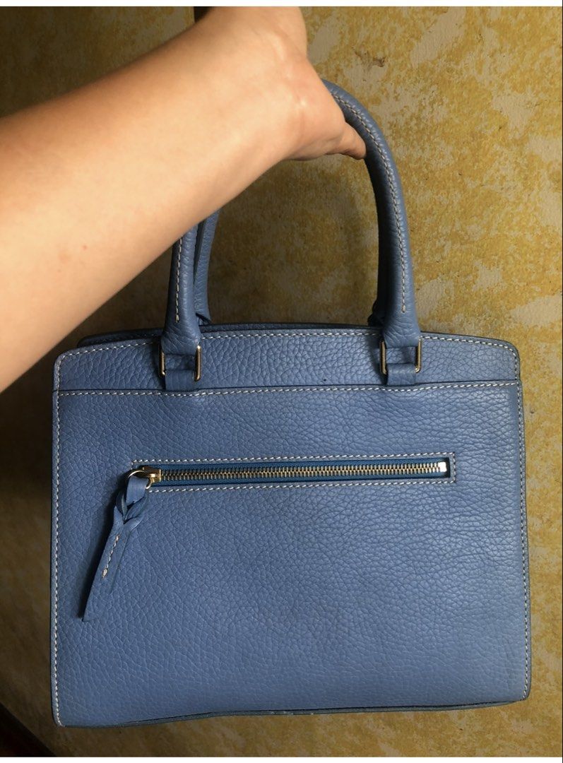 Dooney & Bourke Blue Satchel Handbag (Category: Luxury Bags & Wallets) located in Quezon City. Submitted by cprmob (Listing ID 1436755951, Image 2). Description: - Dooney & Bourke satchel handbag - Light blue pebbled leather exterior - Top handle design - Zipper closure - Back zipper pocket - Includes tag - Gold-tone hardware - Brown interior - Protective metal feet at the bottom.