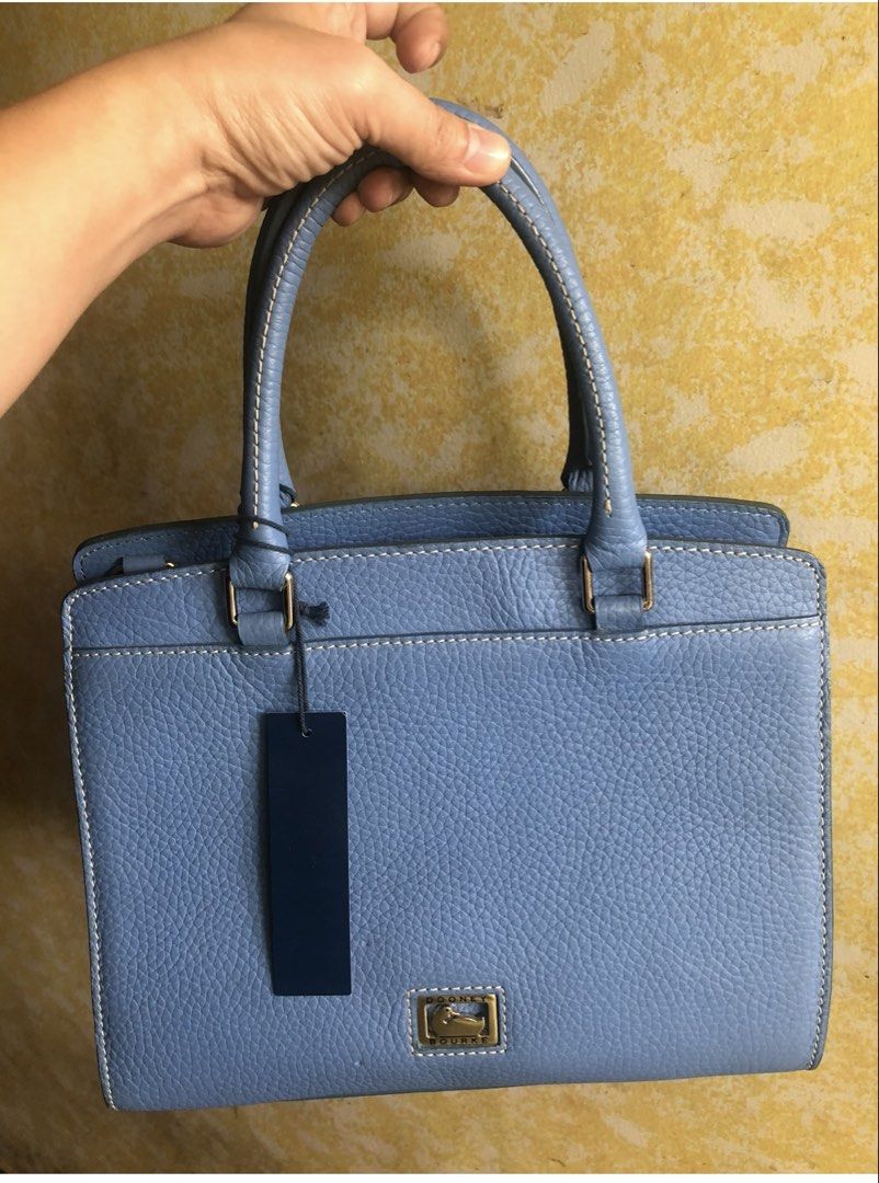 Dooney & Bourke Blue Satchel Handbag (Category: Luxury Bags & Wallets) located in Quezon City. Submitted by cprmob (Listing ID 1436755951, Image 1). Description: - Dooney & Bourke satchel handbag - Light blue pebbled leather exterior - Top handle design - Zipper closure - Back zipper pocket - Includes tag - Gold-tone hardware - Brown interior - Protective metal feet at the bottom.