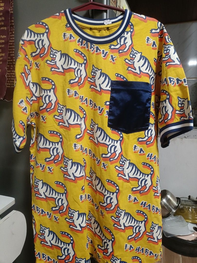 Ed Hardy Tiger Print T-shirt (Category: Tshirts & Polo Shirts ) located in Manila. Submitted by benhurgene30405 (Listing ID 1436741530, Image 2). Description: - Yellow Ed Hardy T-shirt - Features a tiger print design - Navy blue pocket and trim no issue cut hard tag (complete wash tags) - Short sleeves and round neckline.