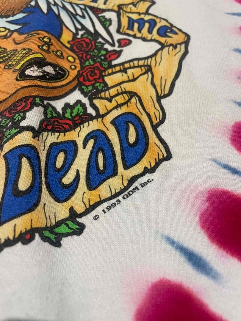 Grateful Dead Tie-Dye T-Shirt (Category: Tshirts & Polo Shirts ) located in Liloan. Submitted by r0yaxx (Listing ID 1436785781, Image 3). Description: - Vintage Grateful Dead tie-dye t-shirt - Dated 1993 - Features skull graphic with band members on the front - Eagle graphic with "Wave That Flag" on the back - Made by Liquid Blue - Red, white, and blue tie-dye pattern.