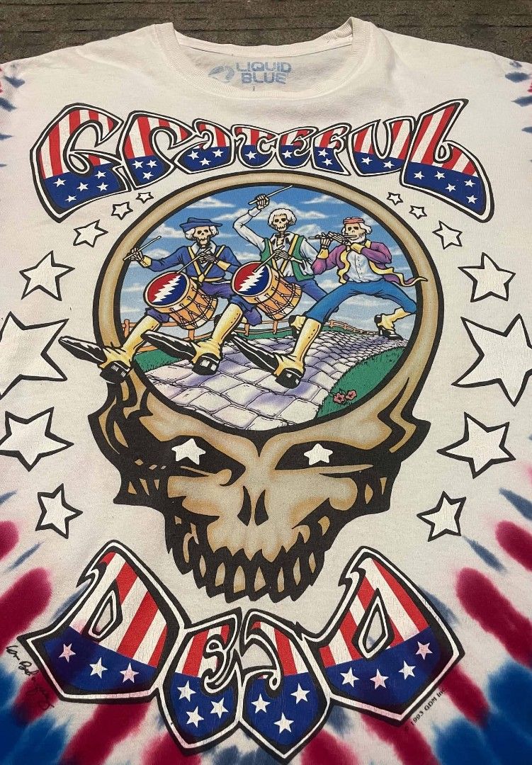 Grateful Dead Tie-Dye T-Shirt (Category: Tshirts & Polo Shirts ) located in Liloan. Submitted by r0yaxx (Listing ID 1436785781, Image 2). Description: - Vintage Grateful Dead tie-dye t-shirt - Dated 1993 - Features skull graphic with band members on the front - Eagle graphic with "Wave That Flag" on the back - Made by Liquid Blue - Red, white, and blue tie-dye pattern.