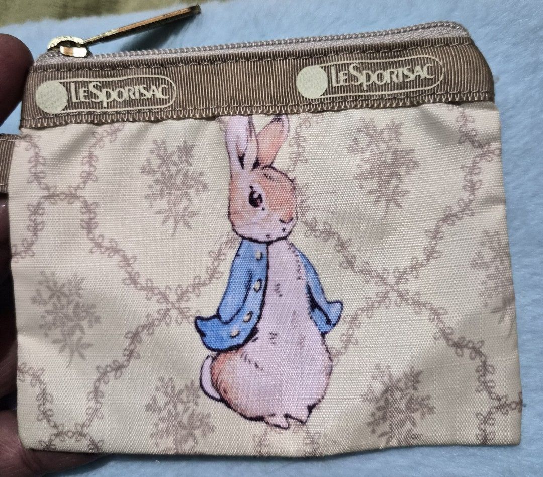 LeSportsac Peter Rabbit Coin Purse (Category: Purses & Pouches) located in Mandaue City. Submitted by chuchi152615 (Listing ID 1436679826, Image 2). Description: - Authentic LeSportsac coin purse - Features a charming Peter Rabbit design - Stylish beige color with a floral pattern - Secure zipper closure - Includes a convenient strap with clasp - Compact and easy to carry - Genuine LeSportsac quality.