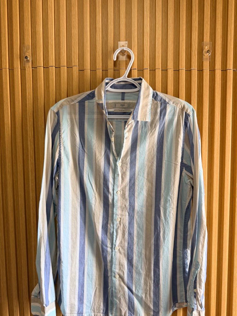 Mango Man Striped Slim Fit Shirt (Category: Tshirts & Polo Shirts ) located in Cebu City. Submitted by dominicviado (Listing ID 1436661686, Image 1). Description: - Mango Man striped shirt - Slim fit - Classic collar - Long sleeves - Button-down front and cuffs - Vertical stripes: blue, beige, light blue - Lightweight fabric - Ideal for casual wear.