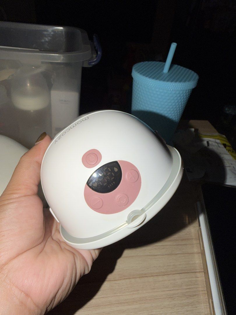 Momcozy Wearable Breast Pump M5 (Category: Breastfeeding & Bottle Feeding) located in Pasig City. Submitted by clairelopez0213 (Listing ID 1436713713, Image 3). Description: - Momcozy wearable breast pump - Includes a carrying case - Two pump units included - Pump units: White with pink accents - Digital display on pump units - Momcozy logo visible - Case features zipper closure and internal compartments **RFS: BF journey ended. Need to declutter