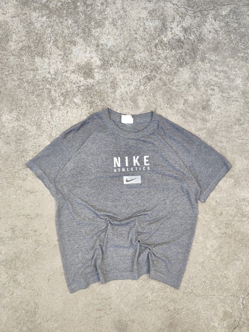 Nike Athletics Gray T-shirt Vintage (Category: Tshirts & Polo Shirts ) located in Polomolok. Submitted by lorinzxx (Listing ID 1436732113, Image 1). Description: - Gray Nike Athletics T-shirt - Size: L - Features Nike logo and "ATHLETICS" print on front - Material: Polyester/cotton blend - Made in USA.