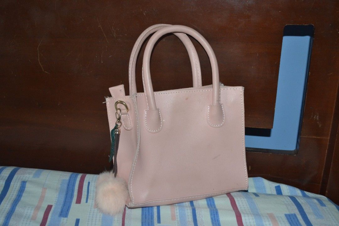 Pink Square Handbag with Pom Pom (Category: Shoulder Bags) located in Valenzuela. Submitted by miss_merix (Listing ID 1436731270, Image 2). Description: - Pink square handbag - Features two handles - Stitched design on the front - Includes a fluffy pom-pom keychain - Zipper closure - Made of smooth material - Stylish and perfect for everyday use.