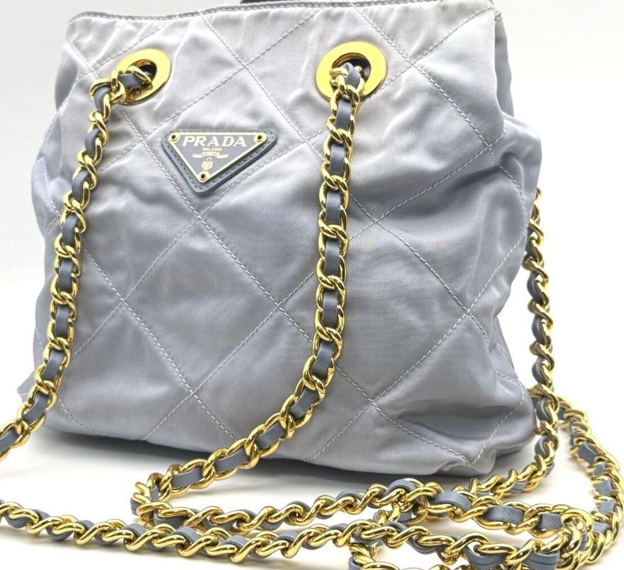 Prada Quilted Chain Shoulder Bag (Rare Color) (Category: Luxury Bags & Wallets) located in Quezon City. Submitted by shopandlearn (Listing ID 1436755732, Image 1). Description: - Authentic Prada handbag - Quilted design - Stylish chain strap (gold & grey leather) - Light blue-grey color - Gold-tone hardware (super clean) - Drawstring closure - Features the iconic Prada triangular logo.