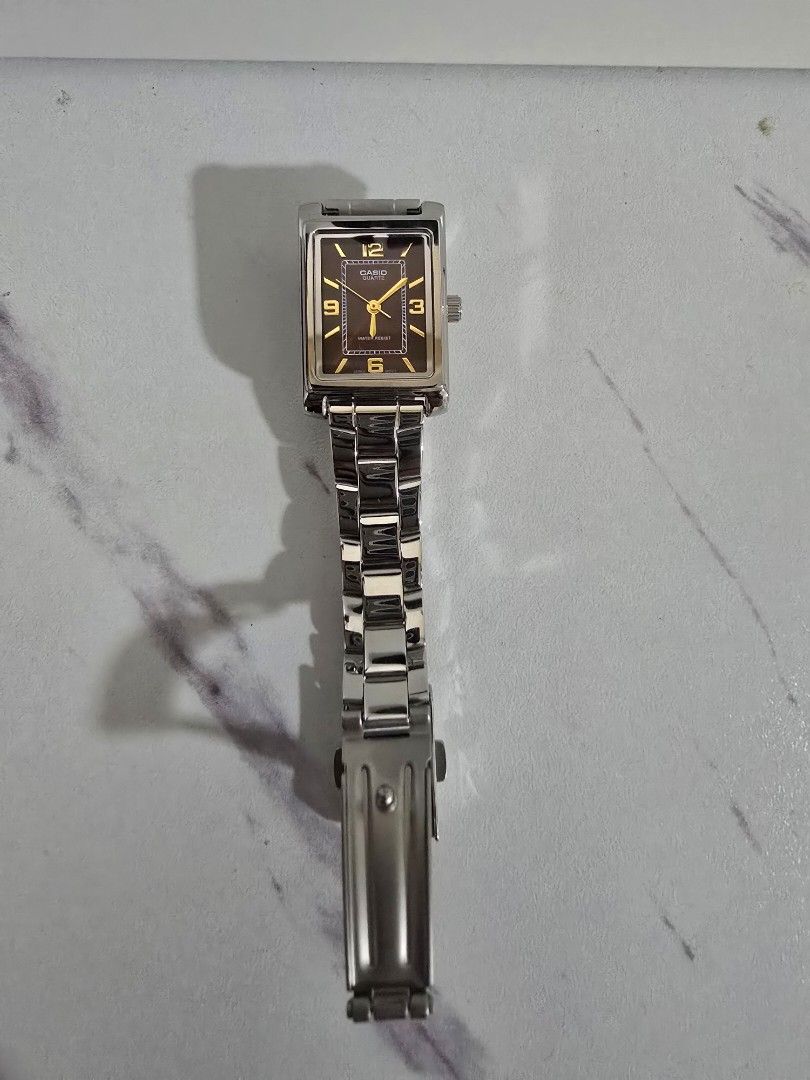 Silver Rectangular Watch (Category: Women's Watches) located in Singapore. Submitted by mohamedridzwan (Listing ID 1436744467, Image 1). Description: - Rectangular watch with a silver strap - Brown dial - Classic design with clear hour markers - Fold-over clasp - Suitable for everyday wear.