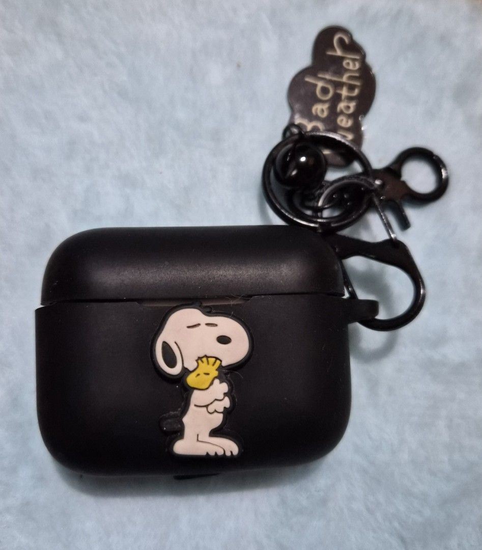 Snoopy AirPods Case with Keychain (Category: Earphones) located in Mandaue City. Submitted by chuchi152615 (Listing ID 1436703791, Image 2). Description: - Black AirPods Pro case - Features a Snoopy design - Includes keychain - Keychain has a "Bad weather?" charm - Matte finish - Attached with a black carabiner clip.