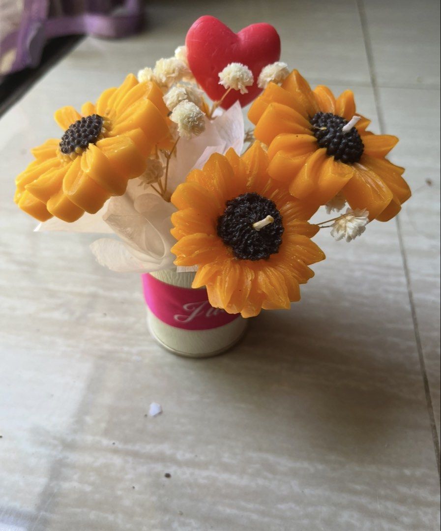 Sunflower Candle Bouquet with Heart (Category: Home Fragrance) located in Manila. Submitted by trendiholic (Listing ID 1436665580, Image 2). Description: - Features three sunflower candles. - Includes small white flowers and a red heart. - Arranged in a decorative pot. - Perfect for adding warmth and beauty. - Ideal as a gift or decorative piece..