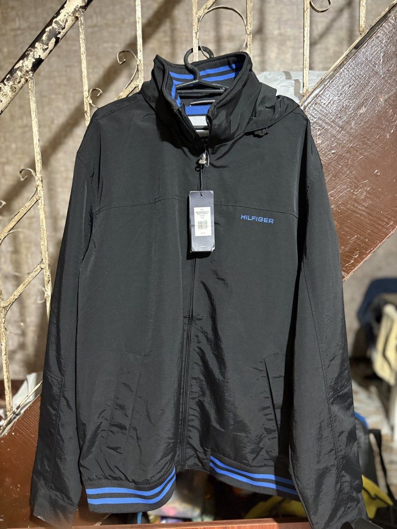 Tommy Hilfiger Men's Lightweight Waterproof Regatta Jacket (Category: Coats, Jackets and Outerwear) located in Manila. Submitted by jazerbisma54088 (Listing ID 1436690813, Image 2). Description: - Tommy Hilfiger men's regatta jacket - Lightweight and waterproof - Color: Black with blue accents - Features a hood - Zipper closure - Tommy Hilfiger logo on chest and hood - Size: XL 21x30 - Waterstop feature .