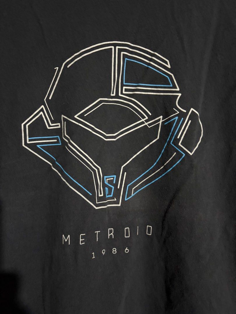 UTGP Nintendo Metroid T-shirt (Category: Tshirts & Polo Shirts ) located in Santa Barbara. Submitted by pickersdelight (Listing ID 1436789384, Image 2). Description: - Black UTGP T-shirt - Features a Metroid design - Graphic: Samus Aran's helmet - Text: "METROID 1986" - Includes Nintendo tag - Size: M Dimension: Width: 21 inches Length: 26 inches Note: colors may vary due to lighting .