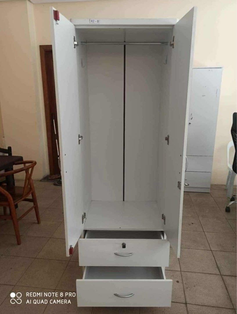 White Wooden Wardrobe with Drawers (Category: Shelves, Cabinets & Racks) located in Manila. Submitted by lykcacamacho (Listing ID 1436679350, Image 1). Description: - White wooden wardrobe - Two doors - Two drawers with silver handles - Includes a hanging rod - Tall and rectangular design - Ideal for storing clothes and other items - Made of wood CASH ON DELIVERY VIA LALAMOVE 09664010899 / 09385133266.