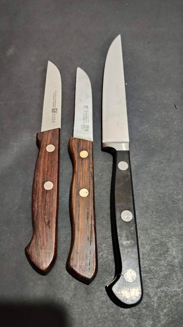 Zwilling J.A. Henckels Knife Set (Category: Knives & Chopping Boards) located in Manila. Submitted by ganisurplus21 (Listing ID 1436675179, Image 1). Description: - Set of three Zwilling J.A. Henckels knives. - Includes: - One large knife with a black handle. - Two smaller knives with wooden handles. - Features the Zwilling J.A. Henckels logo on the blades. - Perfect for various kitchen tasks..