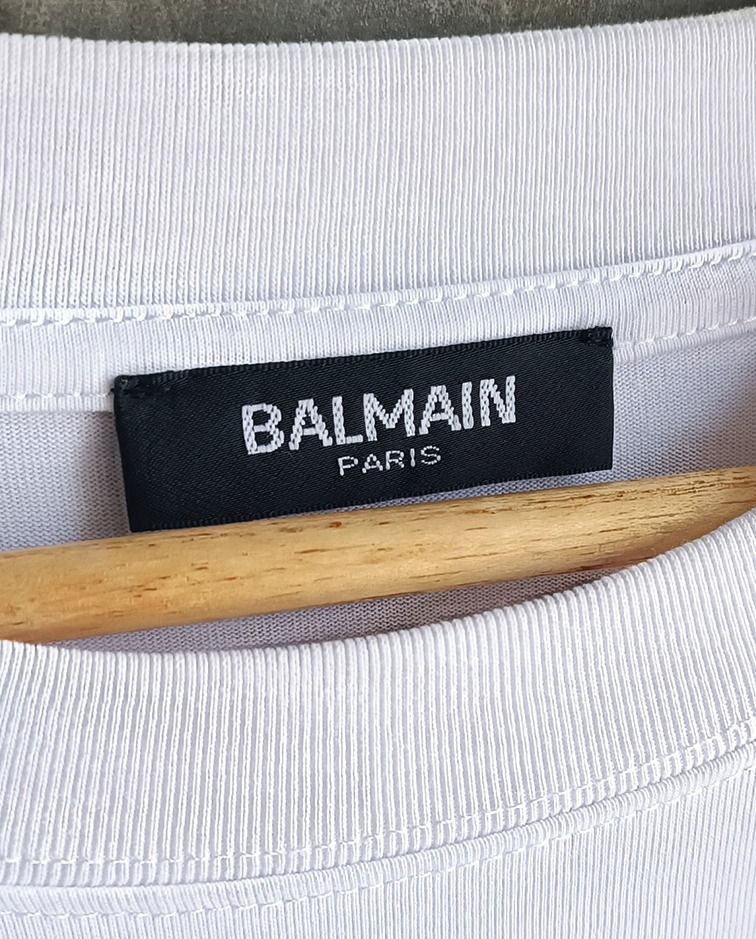 Balmain Paris White T-shirt (Category: Tshirts & Polo Shirts ) located in Guagua. Submitted by retro_finds25 (Listing ID 1436981428, Image 2). Description: Balmain Paris T-shirt - Size: 22 x 27 - Color rate 9/10 - Features the iconic Balmain logo - Made in France - Fabric: 100% cotton - Style: Crew neck, short sleeves - Size: Not indicated.