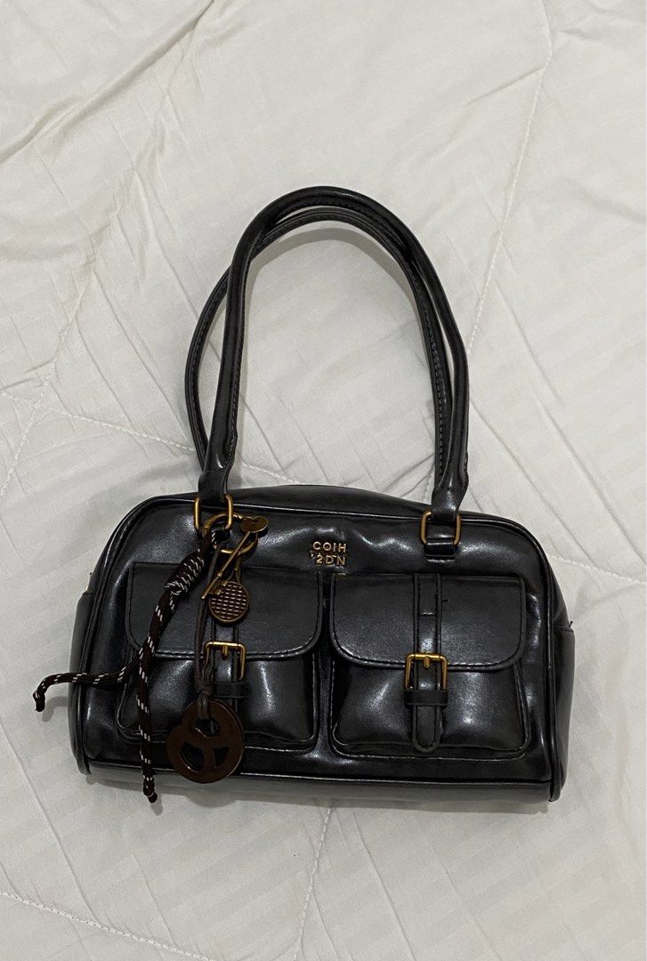 Black Handbag dual pocket (Category: Luxury Bags & Wallets) located in Aliaga. Submitted by dudarling (Listing ID 1436869464, Image 1). Description: - Black handbag - Gold-colored hardware - Two front pockets - Top zipper closure - Two top handles - Decorative tennis racket keychain - Rectangular shape - Glossy material - Black interior.