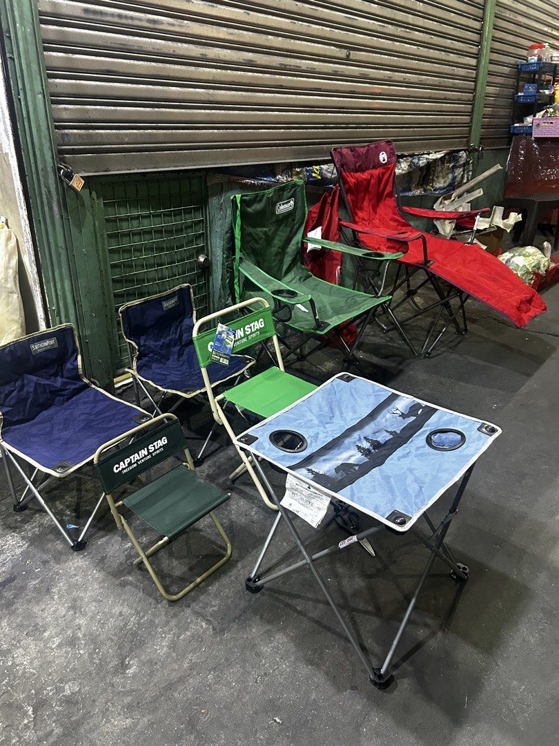 Coleman and Captain Stag Camping Chairs and Table (Category: Hiking & Camping) located in Manila. Submitted by starbalesukandjapansurplus (Listing ID 1436991041, Image 1). Description: Set of camping chairs and a table. Includes various Coleman and Captain Stag chairs in different colors, along with a small folding table with cup holders. Perfect for outdoor activities. The table has a blue surface with a nature-themed design. Some chairs are gre