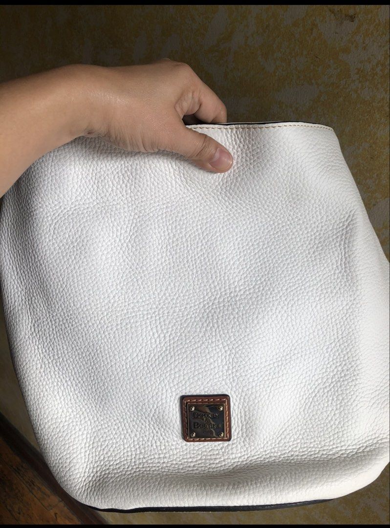 Dooney & Bourke White Leather Shoulder Bag (Category: Luxury Bags & Wallets) located in Quezon City. Submitted by cprmob (Listing ID 1436838277, Image 2). Description: - Dooney & Bourke shoulder bag - White leather exterior - Brown leather straps - Red interior with multiple pockets - Gold-colored brand emblem - Spacious interior - Comfortable shoulder strap.