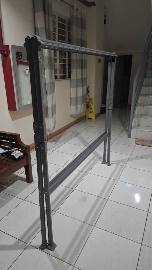 Foldable Clothes Drying Rack (Category: Clothes Drying Rack) located in Manila. Submitted by ccbeltran (Listing ID 1436945198, Image 2). Description: - Foldable clothes drying rack - Suitable for indoor and outdoor use - Features multiple bars for hanging clothes - Sturdy, X-shaped base for stability - Made of metal with a gray finish - Folds up easily for storage - Great for apartments and limited spaces.