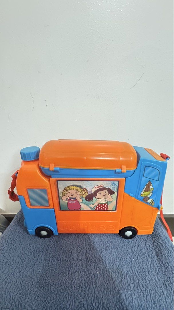 Jollibee Lunch Bus (Category: Vehicle & Diecast Models) located in Paranaque City. Submitted by pengkit (Listing ID 1436895311, Image 2). Description: - Missing spoon - Vintage Jollibee toy truck - Features Jollibee characters and logo - Orange and blue color scheme - Includes a carrying handle - Has wheels - Showcases Jollibee character images on windows - BURGER BOX - HOTDOG CAPSULE - FRIES POCKET - JOLLY JUG.