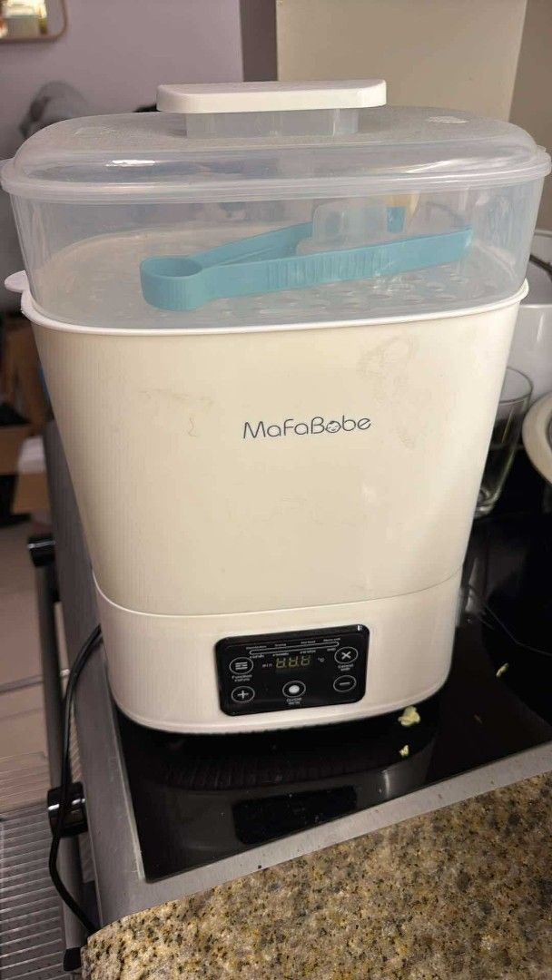 MafaBabe Baby Bottle Sterilizer & Dryer (Category: Breastfeeding & Bottle Feeding) located in Manila. Submitted by ashleycollectionnn (Listing ID 1437014495, Image 1). Description: MafaBabe baby bottle sterilizer. Features a digital display and control panel. Includes a clear top with a blue tong. The sterilizer is cream-colored. Perfect for sterilizing baby bottles and other feeding accessories..