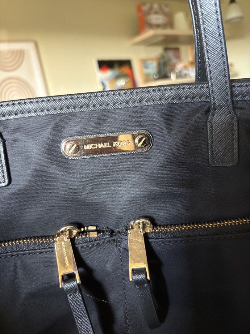 Michael Kors Nylon Black Tote Bag (Category: Tote Bags) located in Pasay City. Submitted by laann00 (Listing ID 1437017327, Image 2). Description: Lightly used Black Michael Kors tote bag with gold-toned hardware. Features two front zipper pockets and a spacious interior with the Michael Kors logo lining. Includes two top handles for carrying. Minor flaw shown in pic ( 1 handle). RFS decluttering..
