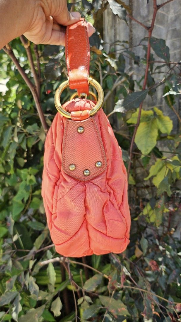 Prada Quilted Hobo Bag (Category: Luxury Bags & Wallets) located in Pamplona. Submitted by luxuryitems_ph (Listing ID 1436832794, Image 3). Description: - Authentic Prada handbag - Quilted design in a vibrant orange color - Top handle for carrying - Elegant gold-tone hardware - Features the classic Prada logo - Unique stitching pattern - Structured shape - Durable leather handle -Has washable dirt on nylon .