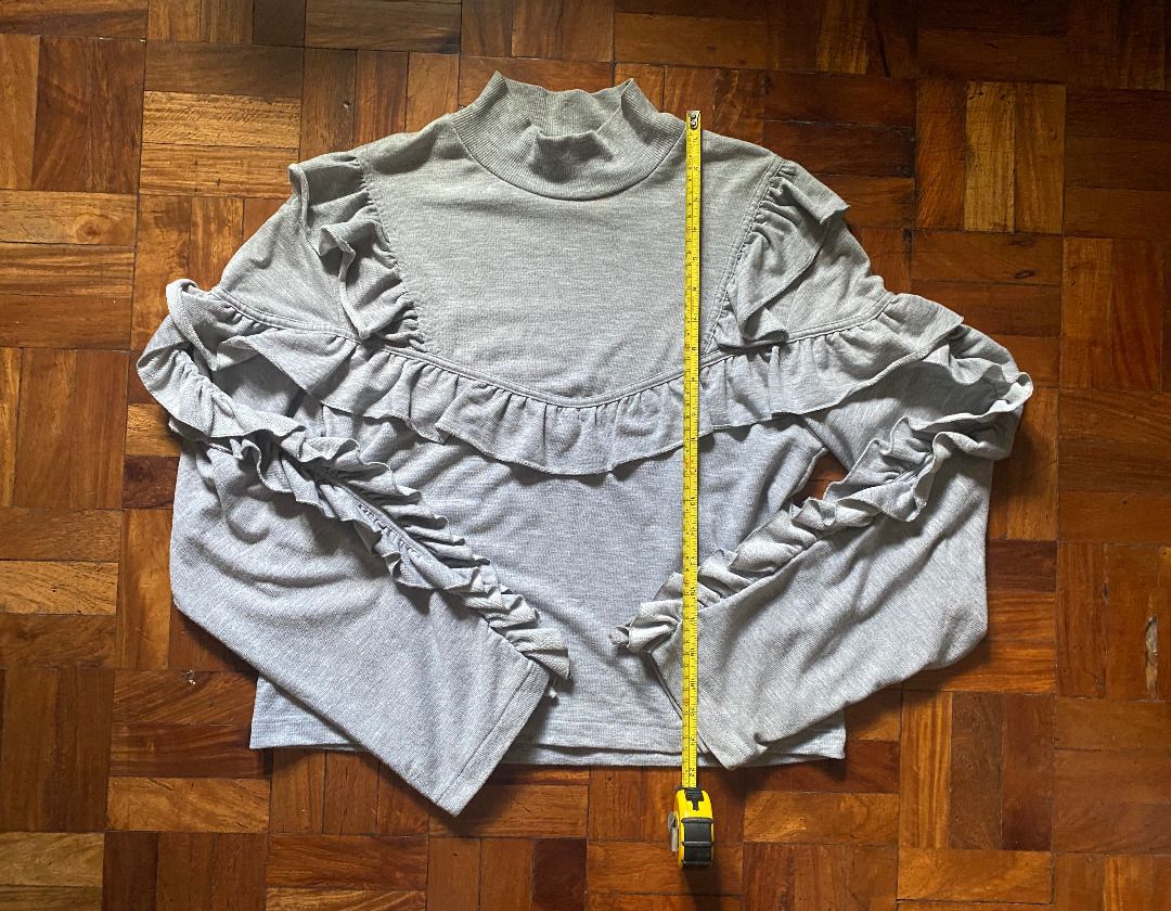 Pre-Loved H&M Gray Ruffle Long Sleeve Blouse (Category: Blouses) located in Mandaluyong City. Submitted by bontiques (Listing ID 1436842054, Image 3). Description: ITEM DESCRIPTION ⭐️ Light gray mock neck blouse ⭐️ Long sleeves with ruffle detailing ⭐️ Lightly fitted silhouette ⭐️ Stretchy fabric ⭐️ Shoulder to Hem: 21 inches ⭐️ Chest: 18 inches ⭐️ Measurements in photos DELIVERY & PAYMENT ⭐️ Gcash QR ⭐️ Lalamove (within 1-2 days or ASAP) ⭐️ J&T 