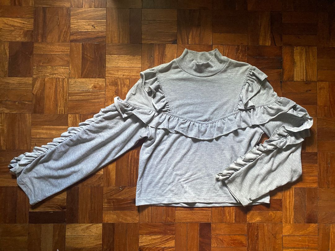 Pre-Loved H&M Gray Ruffle Long Sleeve Blouse (Category: Blouses) located in Mandaluyong City. Submitted by bontiques (Listing ID 1436842054, Image 2). Description: ITEM DESCRIPTION ⭐️ Light gray mock neck blouse ⭐️ Long sleeves with ruffle detailing ⭐️ Lightly fitted silhouette ⭐️ Stretchy fabric ⭐️ Shoulder to Hem: 21 inches ⭐️ Chest: 18 inches ⭐️ Measurements in photos DELIVERY & PAYMENT ⭐️ Gcash QR ⭐️ Lalamove (within 1-2 days or ASAP) ⭐️ J&T 