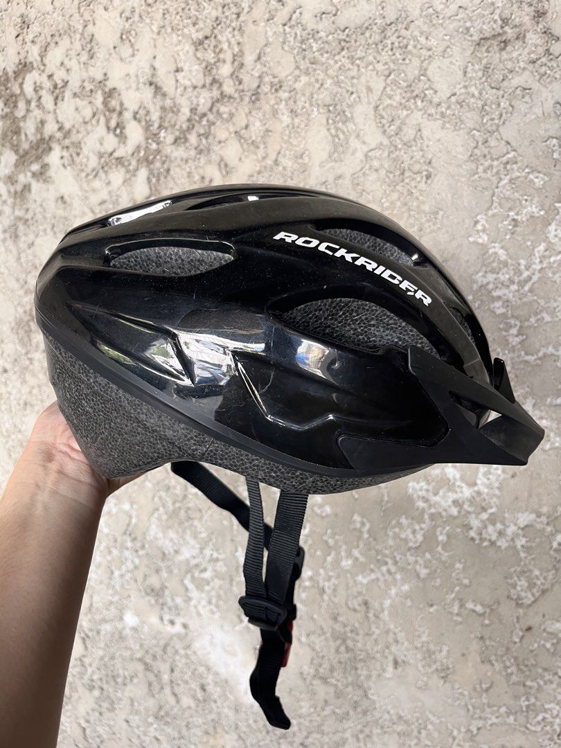 Rockrider Black Helmet (Category: Bicycles) located in Calamba. Submitted by ginopulencia (Listing ID 1436976075, Image 3). Description: Rockrider Mountain Bike Helmet (MTB ST50) Size: Medium 54-58cm Weight: 260g Bought in Decathlon RFS: bought new helmet - Features vents for airflow - Includes a visor for sun protection - Adjustable straps with red buckle - Glossy finish - Perfect for cycling.