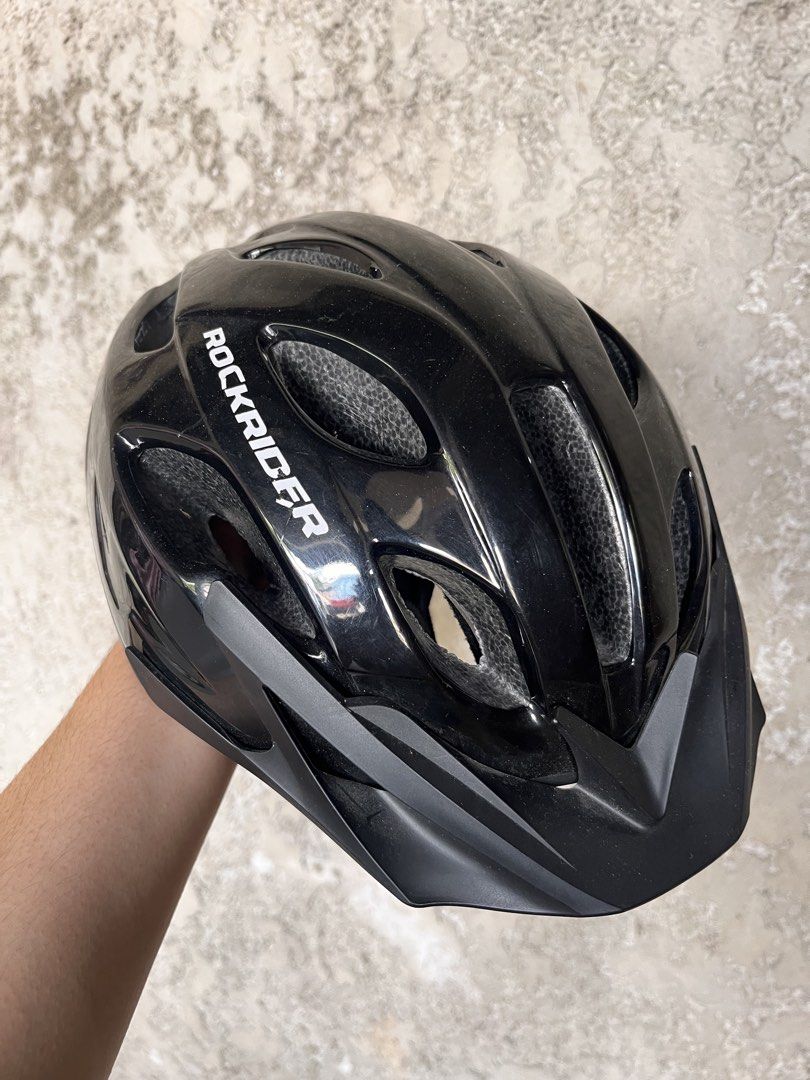 Rockrider Black Helmet (Category: Bicycles) located in Calamba. Submitted by ginopulencia (Listing ID 1436976075, Image 1). Description: Rockrider Mountain Bike Helmet (MTB ST50) Size: Medium 54-58cm Weight: 260g Bought in Decathlon RFS: bought new helmet - Features vents for airflow - Includes a visor for sun protection - Adjustable straps with red buckle - Glossy finish - Perfect for cycling.