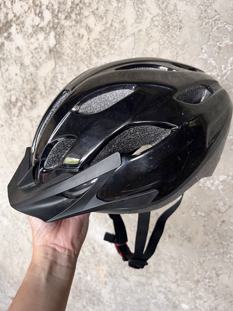 Rockrider Black Helmet (Category: Bicycles) located in Calamba. Submitted by ginopulencia (Listing ID 1436976075, Image 2). Description: Rockrider Mountain Bike Helmet (MTB ST50) Size: Medium 54-58cm Weight: 260g Bought in Decathlon RFS: bought new helmet - Features vents for airflow - Includes a visor for sun protection - Adjustable straps with red buckle - Glossy finish - Perfect for cycling.