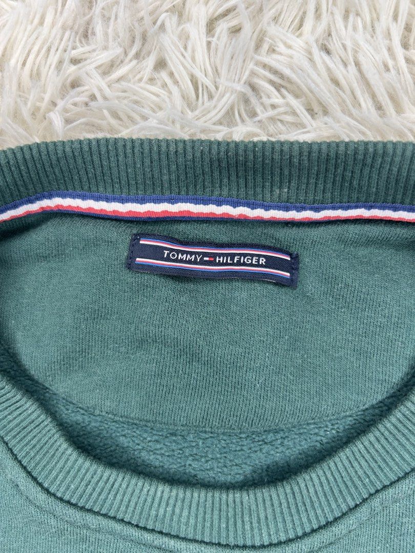 Tommy Hilfiger Green Sweatshirt (Category: Coats, Jackets and Outerwear) located in Baguio. Submitted by Benzelle (Listing ID 1436970481, Image 2). Description: - Tommy Hilfiger sweatshirt - Size: L - Features the Tommy Hilfiger logo on the chest - Includes a small logo patch on the sleeve - Crew neck design - Long sleeves - Made in Portugal.