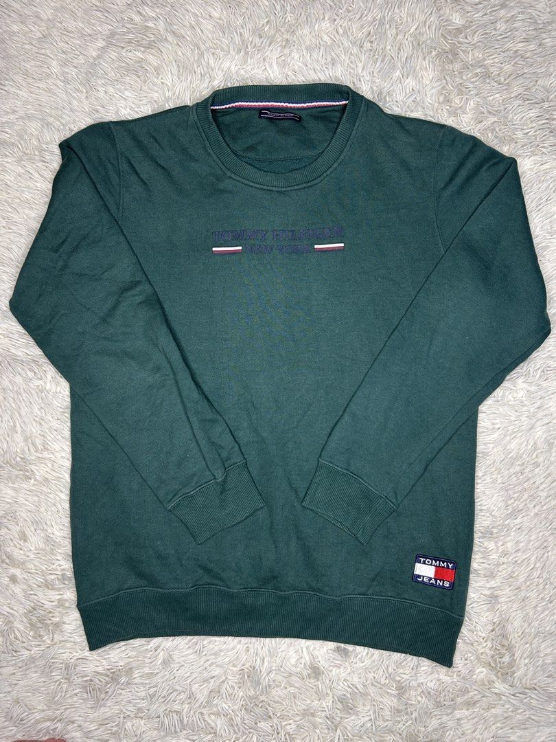Tommy Hilfiger Green Sweatshirt (Category: Coats, Jackets and Outerwear) located in Baguio. Submitted by Benzelle (Listing ID 1436970481, Image 1). Description: - Tommy Hilfiger sweatshirt - Size: L - Features the Tommy Hilfiger logo on the chest - Includes a small logo patch on the sleeve - Crew neck design - Long sleeves - Made in Portugal.