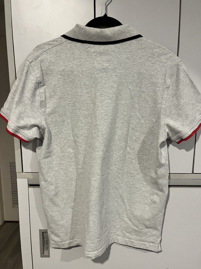 Tommy Hilfiger Polo Shirt (Category: Tshirts & Polo Shirts ) located in Calamba. Submitted by al.nicole (Listing ID 1436942991, Image 2). Description: - Gray Tommy Hilfiger polo shirt - Features the Tommy Hilfiger logo on the chest - Red and black accents on collar and sleeve cuffs - Classic polo collar and short sleeves - Made of soft, breathable fabric - Reduced size due to laundry.