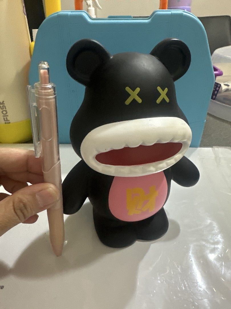 Black Bear Coin Bank Money Box (Category: Vintage Collectibles) located in Cainta. Submitted by shopbyyna (Listing ID 1441213721, Image 3). Description: - Adorable black bear design coin bank. - Convenient slot on the back for easy coin insertion. - Features a unique front design with a pink circle and gold character. - Playful wide open mouth and crossed-out eyes. - Ideal for saving your loose change. - Adds a fun and decorative element to any s