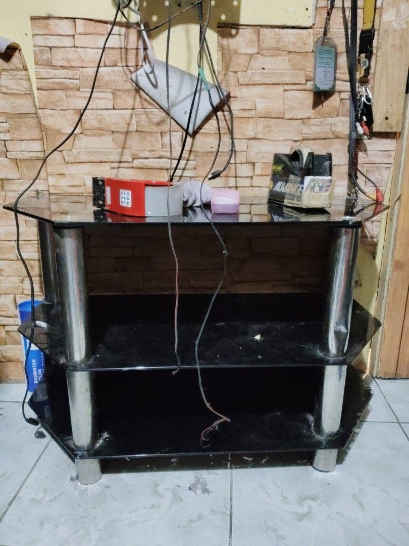 Black Glass TV Stand with Silver Legs (Category: TV Consoles) located in Quezon City. Submitted by luckykikyo (Listing ID 1441322845, Image 2). Description: Need to clean..dirty due to alikabok, nagbbawas gamit lng - Two-tier black glass TV stand - Sturdy silver metal legs - Generous space for media devices and accessories - Ideal for living rooms or bedrooms - Sold as is.